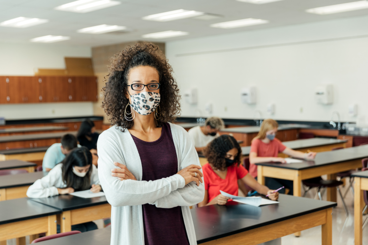 An African-American teaching standing in front of a classroom